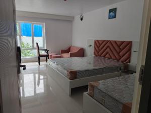 a room with two beds and a chair and a window at Hotel Atithi in Durgāpur