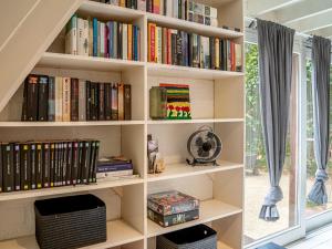a book shelf filled with books next to a window at Boshuisje Rekem - Luka in Lanaken