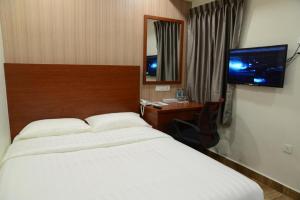 a bedroom with a bed and a desk and a television at Elegant Hotel in Batu Pahat