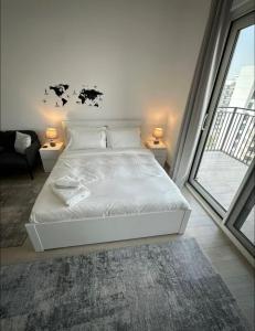 a white bed in a room with a large window at F1 - Lily Studio Waters Edge Yas Island Theme Parks, Canal and Pool View in Abu Dhabi