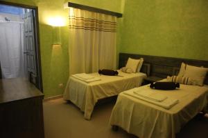two beds in a room with green walls at Vivenda Viviani in Praia