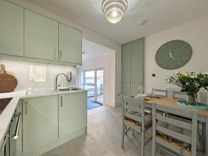 a kitchen with a table and a clock on the wall at Conwy Suite by Seaside Llandudno in Llandudno
