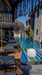 a swimming pool with chaise lounges and umbrellas at a resort at The Grey Alaçatı in Çeşme
