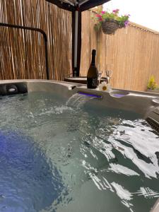 a hot tub with a bottle of wine in it at Secluded Retreat for Family and Friends with Private Hot Tub Dorset in Horton