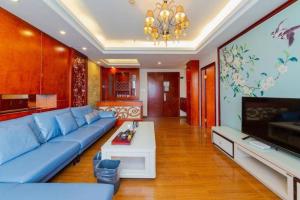 salon z niebieską kanapą i telewizorem w obiekcie GreenTree Inn Guangdong Huizhou Chenjiang Intercity Rail Station Business Hotel w mieście Huizhou