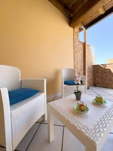 Un patio con una mesa y sillas blancas y una mesa. en LE CASE DI CICCIO - Appartamenti in Centro, en Mazara del Vallo