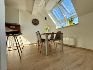 a dining room with a table and chairs and a clock at Allvia apartment in Trnava