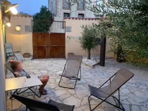 a person sitting at a table and chairs on a patio at Ceret Beautiful Spacious House & Courtyard BBQ in Céret