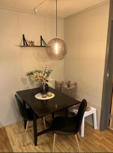 a dining room table with black chairs and a lamp at Hafjell Alpinlandsby in Hafjell