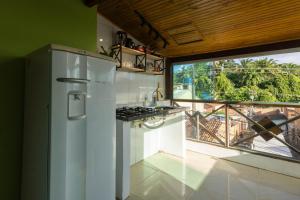 a kitchen with a refrigerator and a large window at Pituba Vile - Apartamento Pituba in Itacaré
