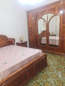 a bedroom with a wooden bed and a large mirror at Casa Verde in Taviano