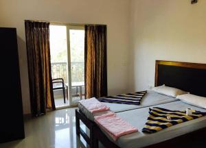 a bedroom with two beds and a large window at Anjuna Plaza Hotel in Anjuna