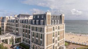 a building on the beach next to the ocean at Appartement bien équipé ultra confort - Sur la plage - Parking privé - gardien in Dinard