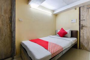 a bedroom with a bed with red pillows on it at Hotel O A One Guest House in Kolkata