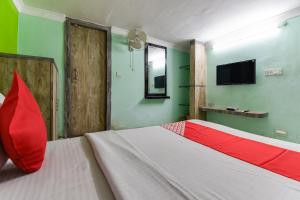 a bedroom with a bed with a red pillow and a tv at Hotel O A One Guest House in Kolkata