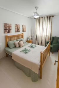 a bedroom with a large bed and a green chair at Apartment Costa Blanca Cabo Roig in Playas de Orihuela