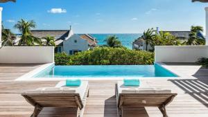 a swimming pool with two lounge chairs and the ocean at Ambergris Cay - Private Island All-Inclusive in Big Ambergris Cay