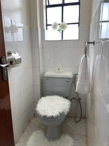 a bathroom with a toilet with a white fuzzy rug at Casa Solenda in Ruaka