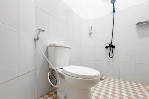 a bathroom with a white toilet with a hose at RedDoorz at Dimens House Sragen in Sragen +15 photos