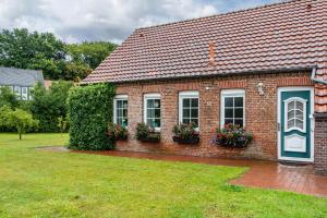 a red brick house with two windows and flowers at Ferienhaus Schenum in Jever