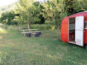 a picnic table and a red trailer in a field at kamp andrea in Šavnik