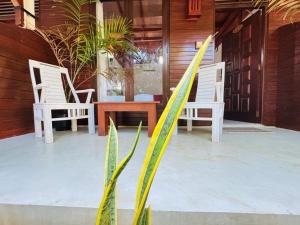 two chairs and a table and a surfboard on a porch at Wild Roots Mirissa in Mirissa