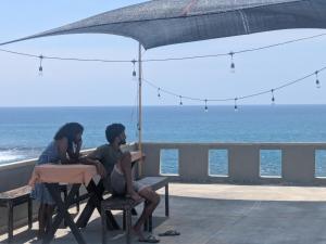 ミディガマ・イーストにあるThe Stables Oceanfront Hotel Midigamaの傘下のテーブルに座る男女