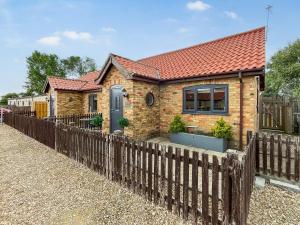 a brick house with a wooden fence at Oxley Cottage in Orby +3 photos