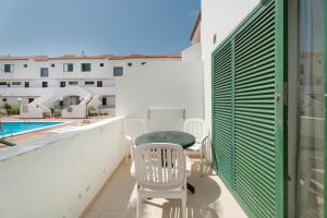 een balkon met een tafel en stoelen en een zwembad bij Alondras Apartamento E107 in Costa Del Silencio