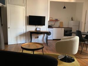 a living room with a couch and a table and a television at Le BARNAVE in Grenoble