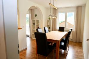 a dining room with a wooden table and black chairs at Ferienwohnung Panoramablick in Nesslau