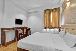 ジャイプールにあるHotel Karma Inn I Hotel Near To Jaipur Airportのベッドと机とテレビのある寝室