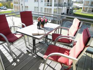 a table and chairs on a balcony with a table and flowers at Meerblick 5 - Großenbrode in Grossenbrode