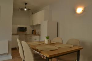 a dining room table with chairs and a white refrigerator at L'Azur - lumineux, fibre, cœur de ville in Ardres