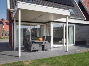 ein offener Pavillon mit Tisch und Stühlen auf einer Terrasse in der Unterkunft Holiday home with whirlpool and sauna in a quiet area in Zeeland in Colijnsplaat