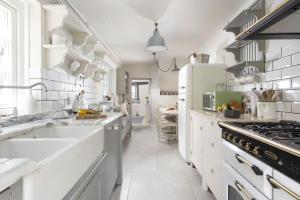 a white kitchen with a large sink and a stove at Almond Cottage - Pets welcome - Free Parking - Garden in Hayle