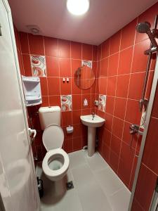 a red tiled bathroom with a toilet and a sink at Guest Rooms Comfort 2 City Center in Plovdiv