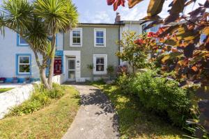 a house with a palm tree in front of it at Almond Cottage - Pets welcome - Free Parking - Garden in Hayle