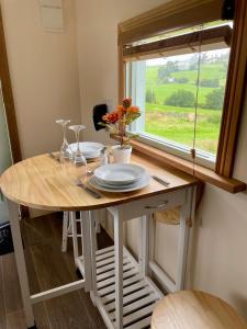 a table with plates and glasses on it with a window at Kerrib Farm Shepherds Hut in Pomeroy