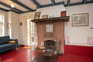 a living room with a brick fireplace with a blue couch at Vakantiewoning Hosa Semna in de duinen van Vrouwenpolder in Vrouwenpolder