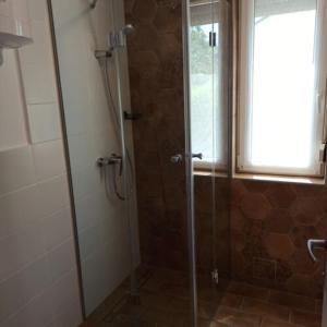 a shower with a glass door in a bathroom at Kati Appartmann in Balatonberény +6 photos