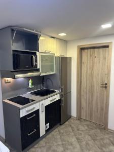 a kitchen with a sink and a microwave and a refrigerator at Guest Rooms Comfort 2 City Center in Plovdiv