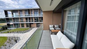 OlsztynにあるOmega Lake Premium Apartmentsの白い家具と建物のあるアパートのバルコニー