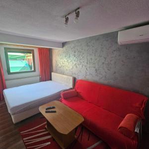a small room with a red couch and a table at Apartment Savanovic in Banja Luka