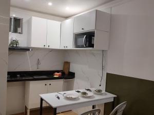 a kitchen with white cabinets and a white table and chairs at Studio 102 Cop 30 in Curro Velho