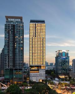 a tall building with lights on it in a city at Ascott Embassy Sathorn Bangkok in Bangkok