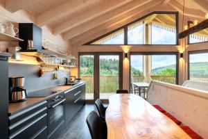 a kitchen with a wooden table and a large window at Schwarzwalddeck Deckhäuser in Bad Herrenalb