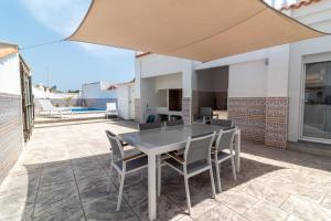 a patio with a table and chairs under a large umbrella at Global Properties, Deslumbrante casa en la playa de Sagunto in Sagunto