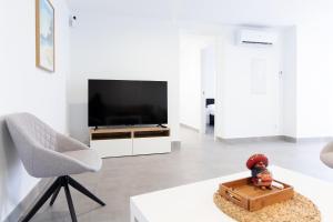 a living room with a television and a chair at Global Properties, Deslumbrante casa en la playa de Sagunto in Sagunto