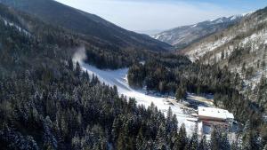 a snow covered mountain with trees and a ski lodge at Kartala Ski Resort in Blagoevgrad